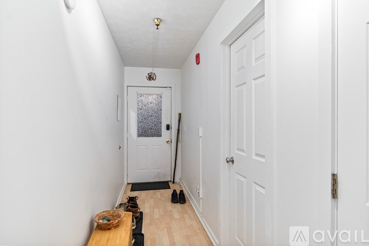 A hallway with a door on the right and a basket on the floor.