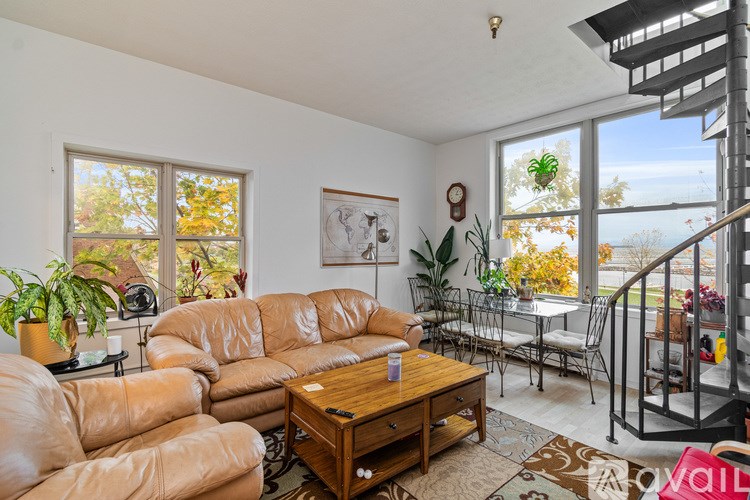 A room with wooden flooring and large windows overlooking a body of water.