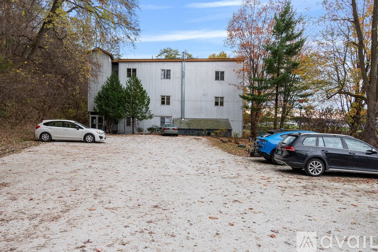 A white building with a grey car and a black car parked in front.