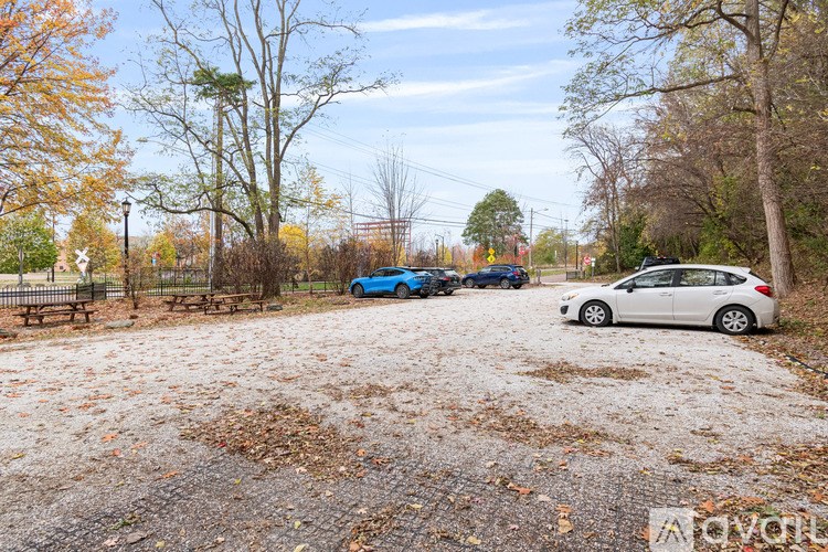 A gravel parking lot with a white car and a blue car parked in it.