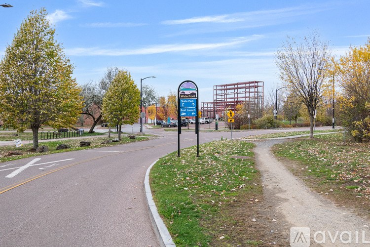 A street sign on a pole in the middle of a road with trees on the side.