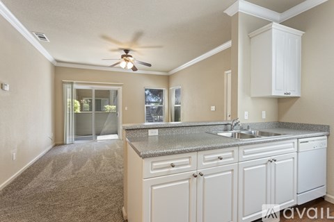 A kitchen with a fan on the ceiling and a sink in the middle.