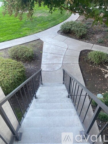 A set of stairs with a metal railing leading up to a grassy area.