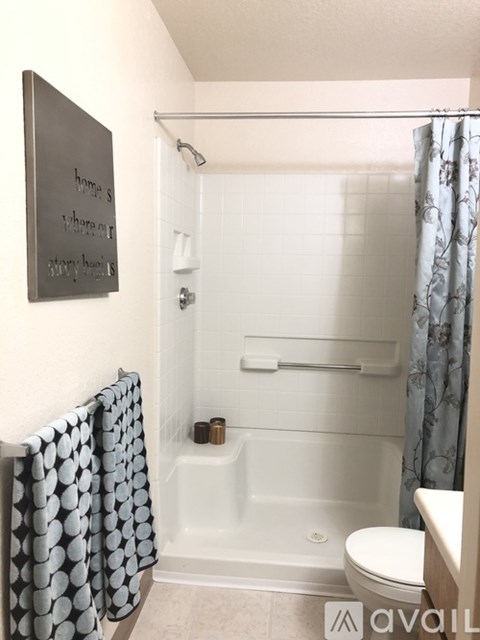 A bathroom with a toilet, a bathtub with a shower curtain and a sign on the wall.
