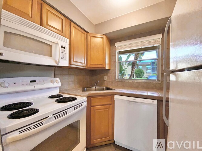 A kitchen with white appliances and wooden cabinets.