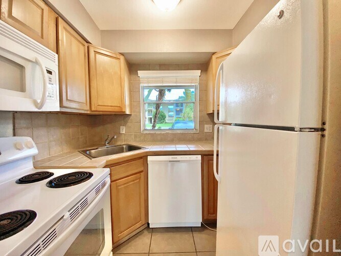 A kitchen with white appliances and wooden cabinets.