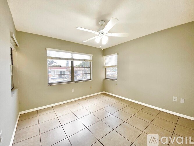 A spacious room with a ceiling fan and tiled flooring.