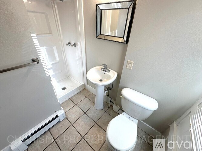 A white toilet sits next to a white sink in a small bathroom.