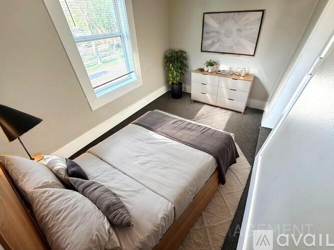 A bedroom with a bed, nightstand, and a window.