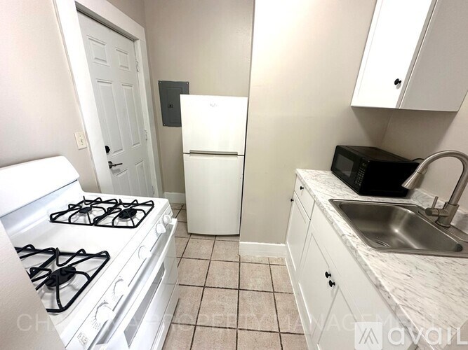 A small kitchen with a white stove, white fridge, and white cabinets.