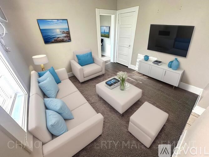 A living room with a white couch, a grey carpet, and a painting on the wall.