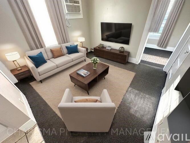 A living room with a white couch, a coffee table, and a television.