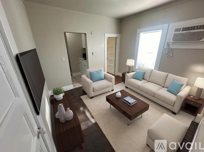 A living room with a white couch, a brown coffee table, and a flat screen TV.