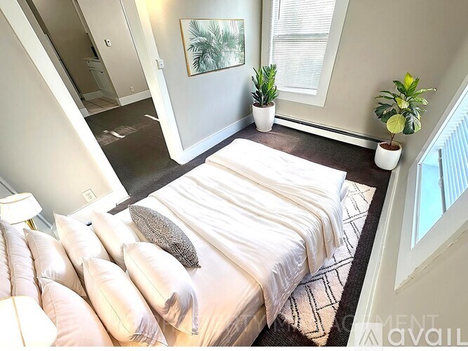 A bedroom with a bed, pillows, and plants.