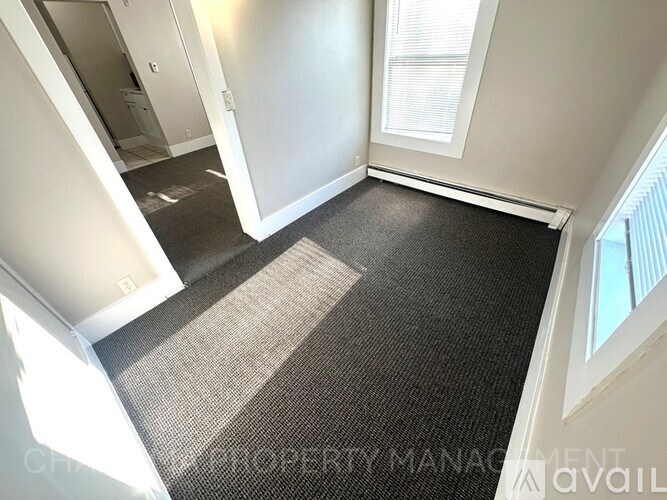 A room with a carpeted floor and a window.