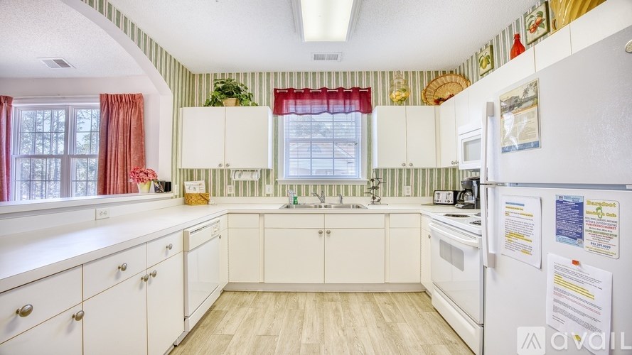 A kitchen with white cabinets and a white refrigerator.