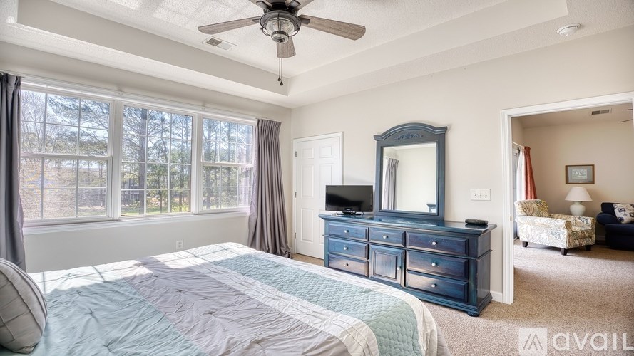 A bedroom with a large bed, a dresser, and a ceiling fan.