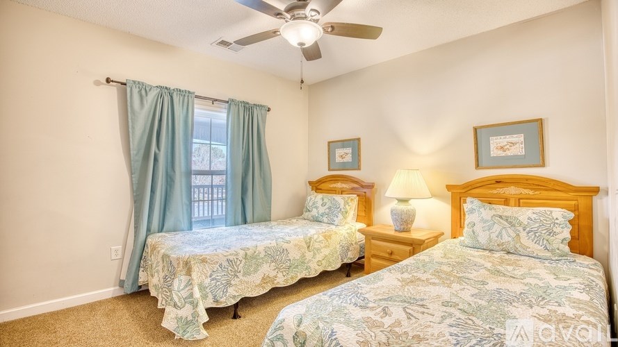 Two twin beds with matching blue and white bedding in a room with a ceiling fan.