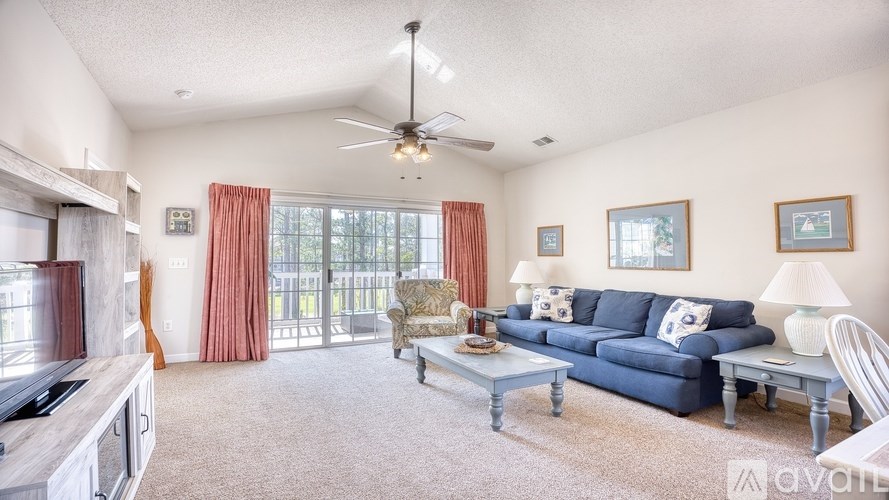 A living room with a blue couch and a ceiling fan.