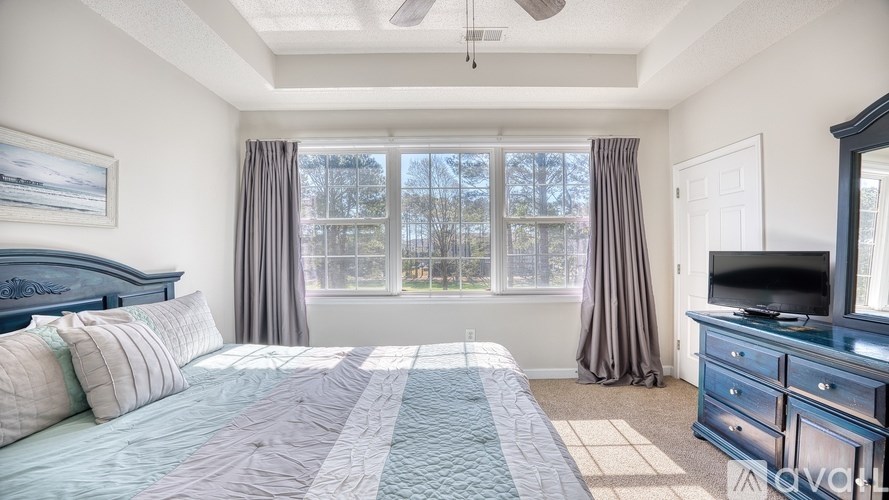 A bedroom with a large bed, a dresser, and a television.