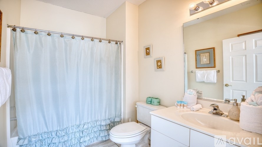 A bathroom with a white toilet, sink, and shower curtain.