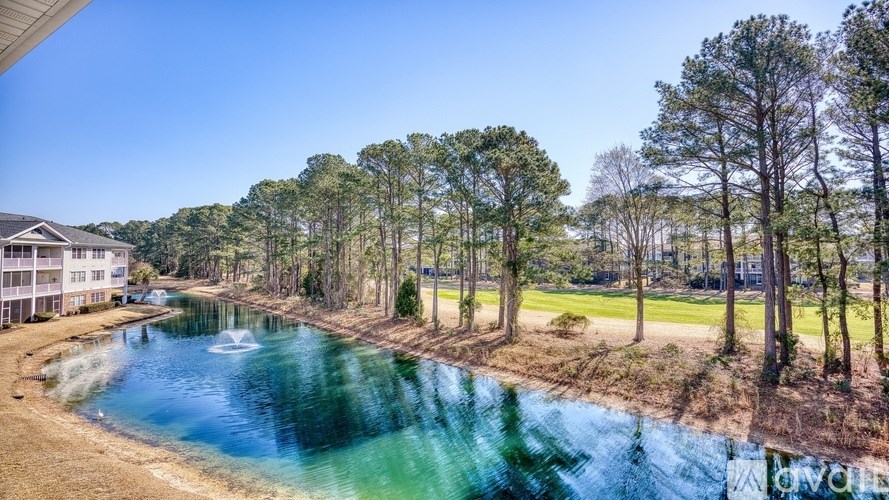A serene landscape with a pond and a building in the background.