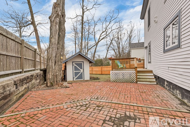 A backyard with a brick patio and a shed.