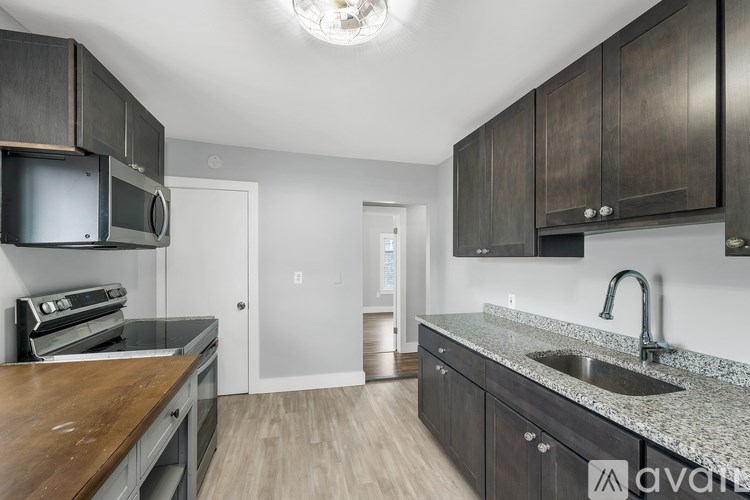 A kitchen with dark wood cabinets and a granite countertop.