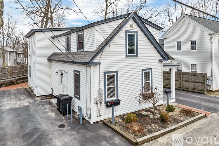 A white house with a black roof and a mailbox on the front.