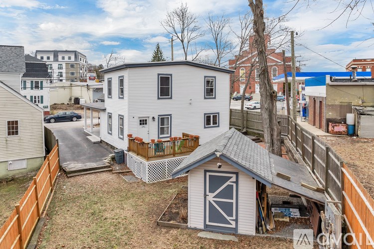A white house with a grey roof and a wooden fence.