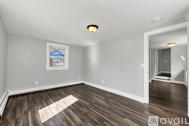 A room with wooden flooring and a window with a view of a building.