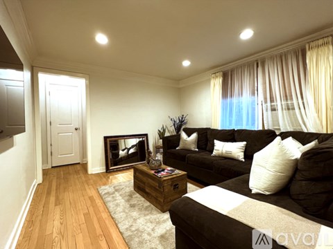 A living room with a brown couch and a wooden floor.