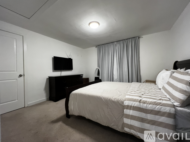 A bedroom with a bed, a television, and a dresser.