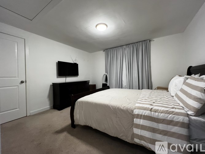 A bedroom with a bed, a television, and a dresser.