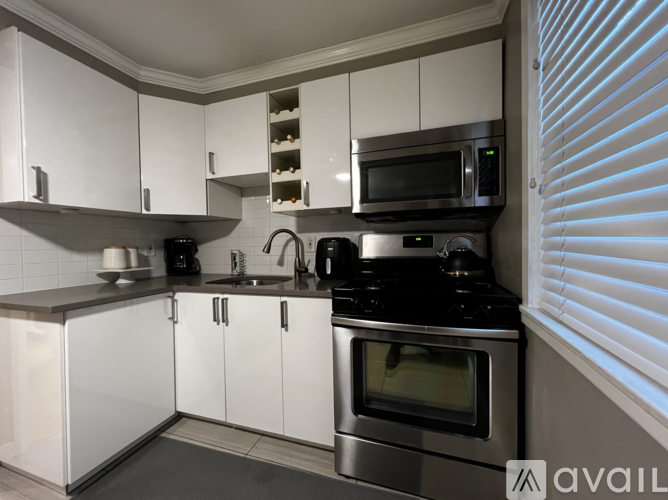A modern kitchen with white cabinets and stainless steel appliances.