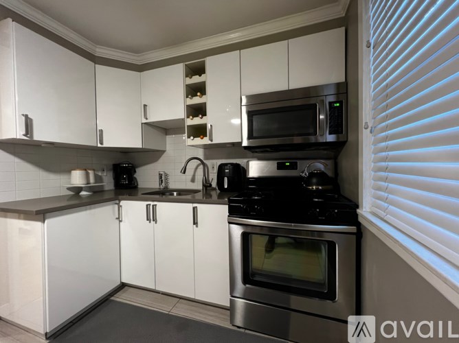 A modern kitchen with white cabinets and stainless steel appliances.