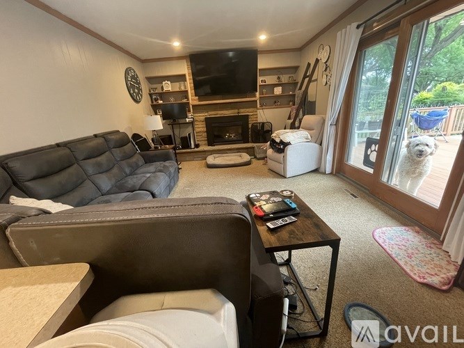 A living room with a black leather couch, a coffee table, and a fireplace.