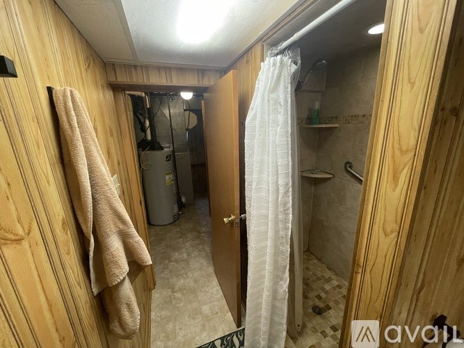 A bathroom with a towel hanging on the wall and a shower curtain.