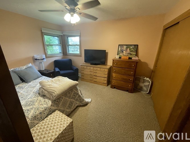 A bedroom with a bed, a chair, a dresser, and a television.