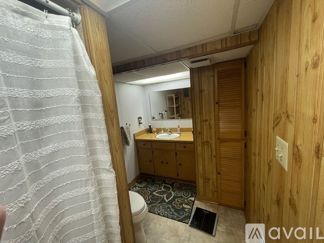A bathroom with wooden walls and a white towel hanging on the door.