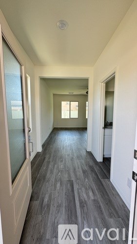 A long hallway with wood floors and white walls.