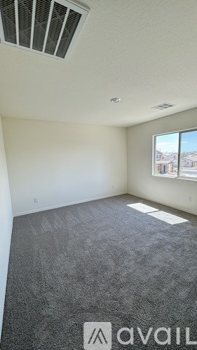A room with a carpeted floor and a window showing a view of houses.
