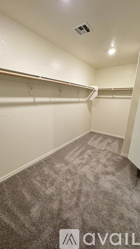 A walk in closet with a carpeted floor and white walls.