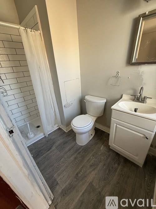 A bathroom with a toilet, sink, and shower.