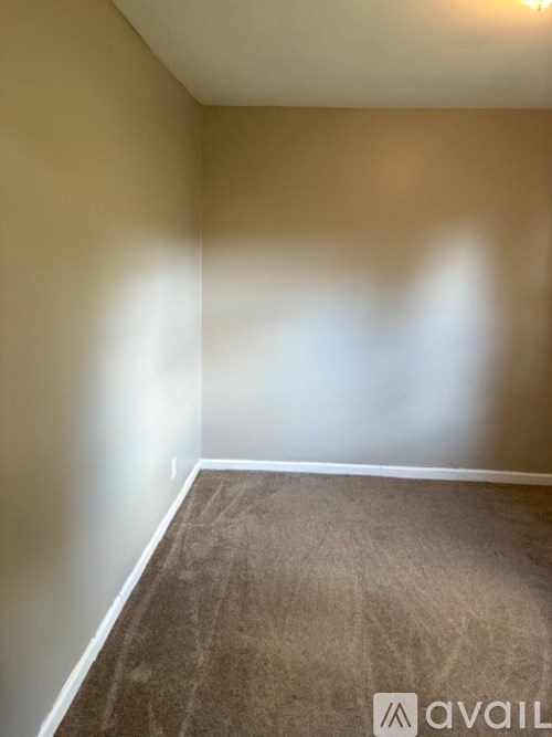 A room with a carpeted floor and a wall.