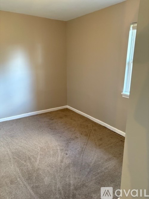 A room with a carpeted floor and a window on the wall.