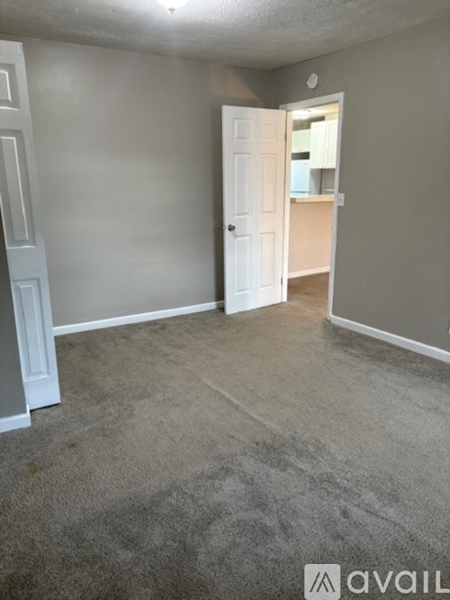 A room with a carpeted floor and a doorway leading to another room.