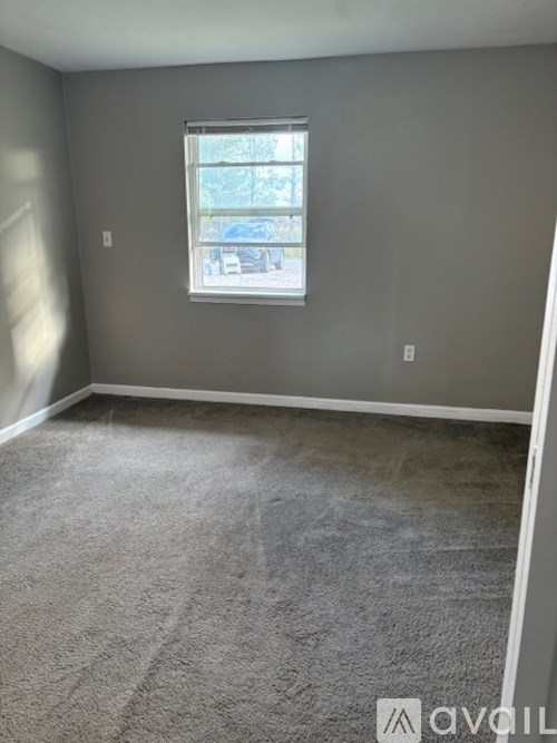 A room with a carpeted floor and a window.