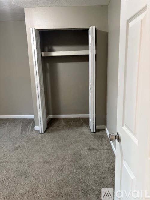 A white closet with a door and shelves.