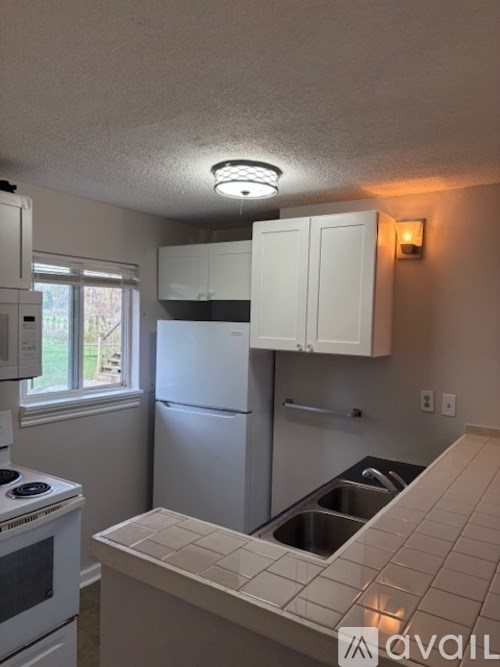A kitchen with white appliances and cabinets.